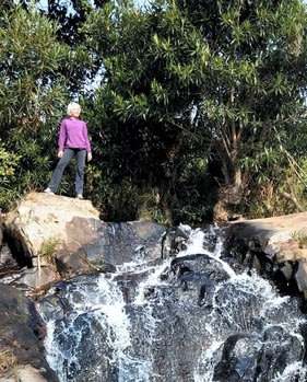 Chantaul Jordan standing at the top of a waterfall.